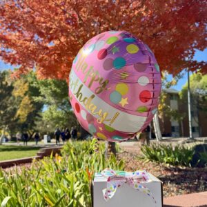white cake box with bow and birthday balloon attached